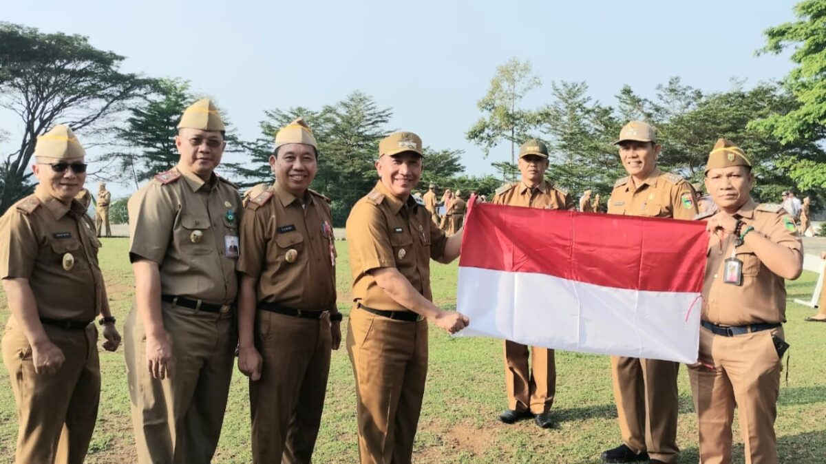 Pj Bupati Tanggamus, Mulyadi Irsan saat menyerahkan bendera merah putih di lapangan Pemkab setempat, Senin 29 Juli 2024. Foto : Kominfo Tanggamus.