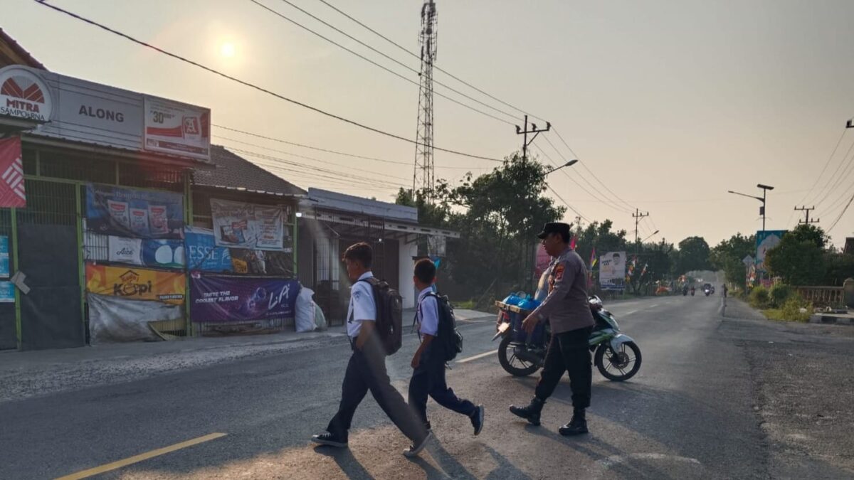 Anggota Polsek Pugung Polres Tanggamus saat menyebrangkan pelajar, Selasa 3 September 2024.