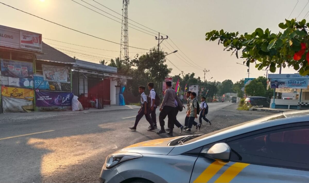 Aktifitas anggota Polsek Pugung Tanggamus sebrangkan jalan di Jalan Rantau Tijang, Rabu 18 September 2024 | Asrul Ariski/Media Prioritastv.com.