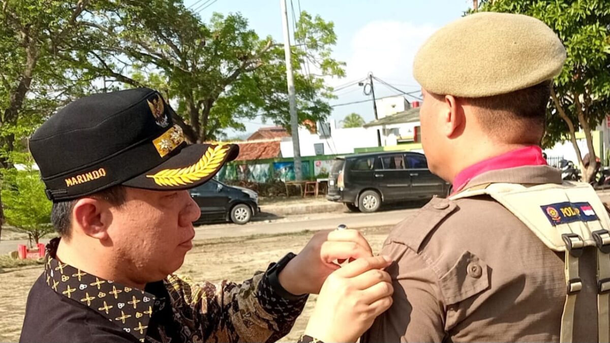 Pj Bupati Pringsewu Marindo Kurniawan saat menyematkan pita tanda pengamanan Pilkada 2024, Jumat 27 September 2024.