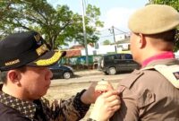 Pj Bupati Pringsewu Marindo Kurniawan saat menyematkan pita tanda pengamanan Pilkada 2024, Jumat 27 September 2024.