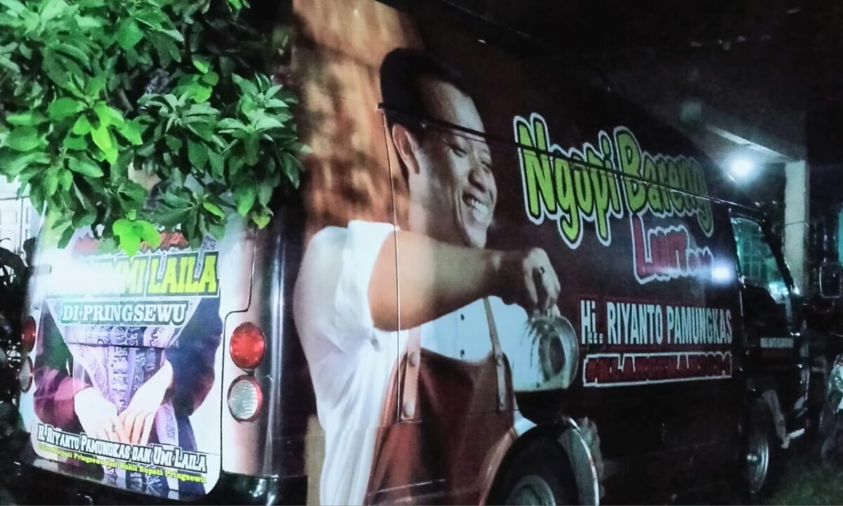 Mobil beratribut Paslon Bupati Pringsewu berada di tempat ibadah saat pelaksanaan Maulid Nabi Muhammad SAW di Masjid Nurul Barokah, Kamis 27 September 2024.