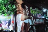 Mobil beratribut Paslon Bupati Pringsewu berada di tempat ibadah saat pelaksanaan Maulid Nabi Muhammad SAW di Masjid Nurul Barokah, Kamis 27 September 2024.