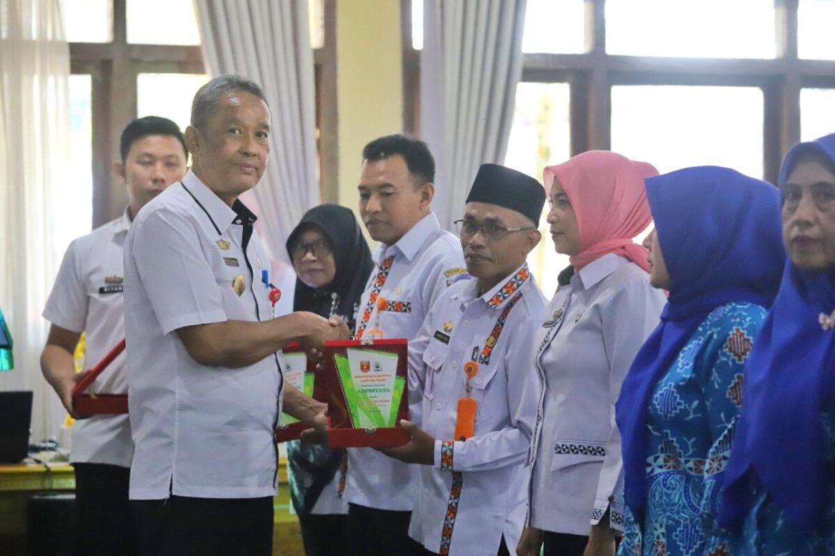Wasisno Sembiring menyerahkan plakat Adiwiyata saat  Bimtek PBLHS di Aula Kagungan Setdakab, Kamis, 10 Oktober 2024. Kegiatan ini dihadiri oleh para perwakilan guru sekolah di Kabupaten Lampung Barat.