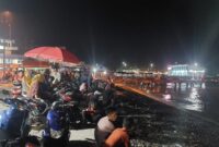 Masyarakat berkumpul di tepian pantai duduk-duduk menunggu kemunculan fenomena ikan naik ke daratan di Pantai Dermaga Dua Kota Agung, Tanggamus, Minggu 9 November 2024, malam | Herdi/Media Prioritastv.com.