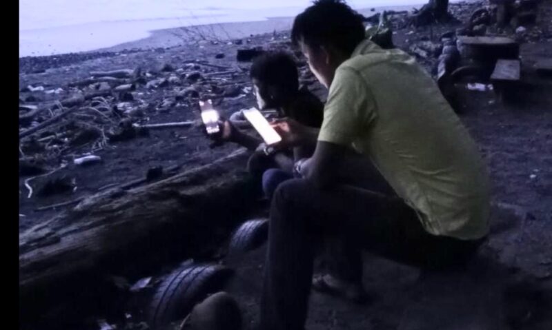 Masyarakat Pekon Badak saat mencari Signal Komunikasi Data di Pinggir Pantai, Senin 11 November 2024.