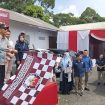 Pj Bupati Tanggamus Muyadi Irsan mengangkat bendera tanda pelepasan logistik Pilkada 2024 ke Cukuh Balak dan Pematang Sawa di Gudang Logistik KPU Pekon Gisting Atas, Minggu 24 November 2024 | Herdi/Media Prioritastv.com.