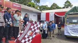 Pj Bupati Tanggamus Muyadi Irsan mengangkat bendera tanda pelepasan logistik Pilkada 2024 ke Cukuh Balak dan Pematang Sawa di Gudang Logistik KPU Pekon Gisting Atas, Minggu 24 November 2024 | Herdi/Media Prioritastv.com.