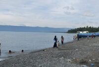 Wisatawan menikmati ombak pantai Muara Indah, Kota Agung, Tanggamus, Rabu 25 Desember 2024 | Herdi/Media Prioritastv.com.