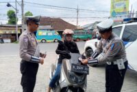 Anggota Sat Lantas Polres Tanggamu saat memberikan leaflet imbauan kepada pengendara motor di Jalan Ir Juanda, Kota Agung, Jumat 14 Februari 2025.