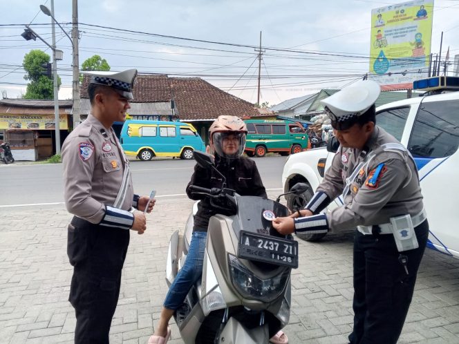 
 Anggota Sat Lantas Polres Tanggamu saat memberikan leaflet imbauan kepada pengendara motor di Jalan Ir Juanda, Kota Agung, Jumat 14 Februari 2025.