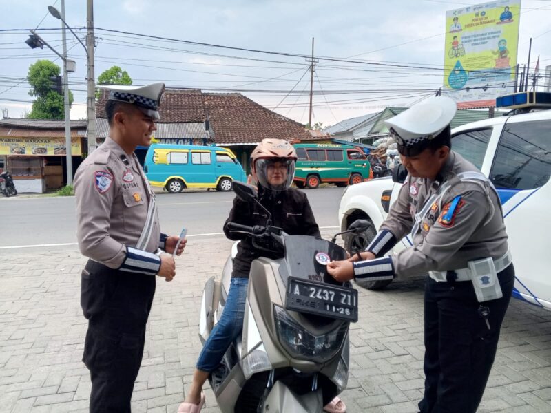 Anggota Sat Lantas Polres Tanggamu saat memberikan leaflet imbauan kepada pengendara motor di Jalan Ir Juanda, Kota Agung, Jumat 14 Februari 2025.