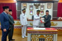 Penyerahan cindramata dari Pj Bupati Tanggamus 2023 - 2025 Mulyadi Irsan kepada Bupati Tanggamus 2025 - 2030 Moh Saleh Asnawi usai penandatangan memory sertijab, Kamis 6 Februari 2025 | Herdi/Media Prioritastv.com.
