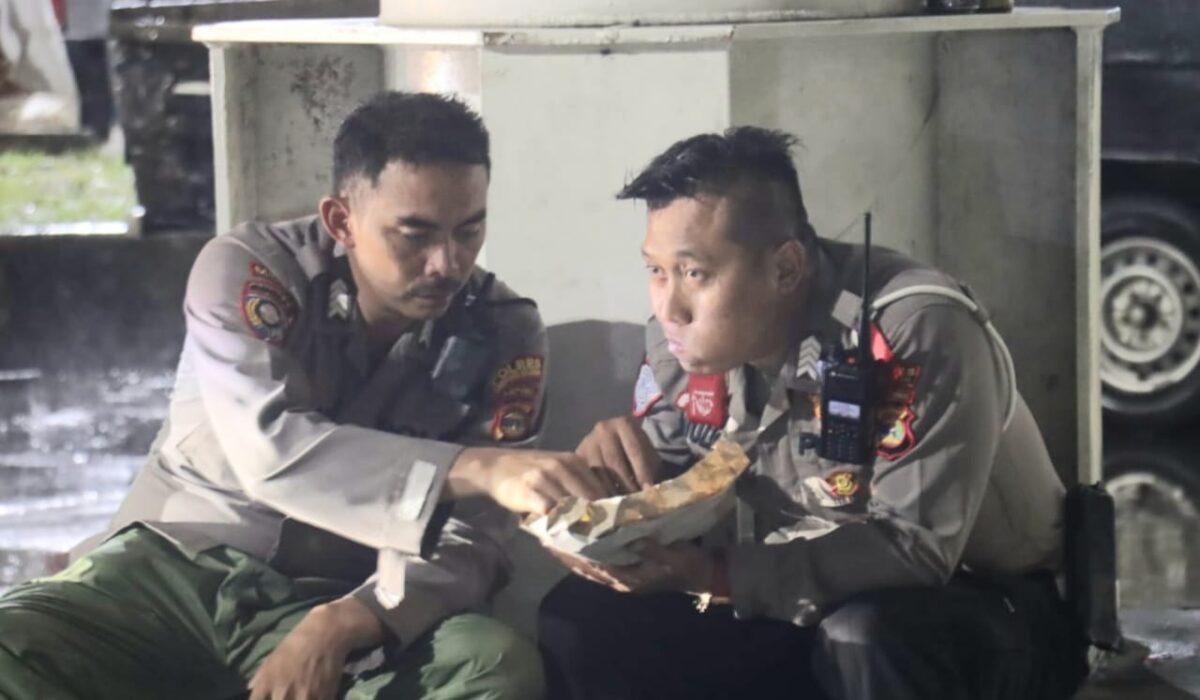 Potres Bripka Baim dan Bripka Mulya berbagi nasi bungkus saat hujan deras di dermaga Bakauheni, Lampung Selatan, Rabu 2 April 2025 | Dok. Istimewa.