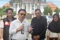 Kuasa hukum Gindha Ansori Wayka (berkemeja putih, memegang mikrofon) bersama pasangan Pingi Sudarsono dan Patonah (kanan) memberikan keterangan pers di depan Pengadilan Negeri Menggala, Kabupaten Tulang Bawang, Lampung, usai pencabutan gugatan oleh pihak BRI terkait sengketa rumah yang mereka alami, Kamis (22/5/2025).