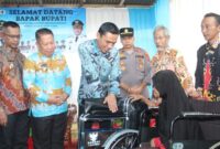Wabup Tanggamus, Agus Suranto saat menyerahkan kursi roda kepada salah satu penerima di UPTD Puskesmas Bandar Negeri Semuong, Kamis 22 Mei 2025 | Herdi/Media Prioritastv.com.