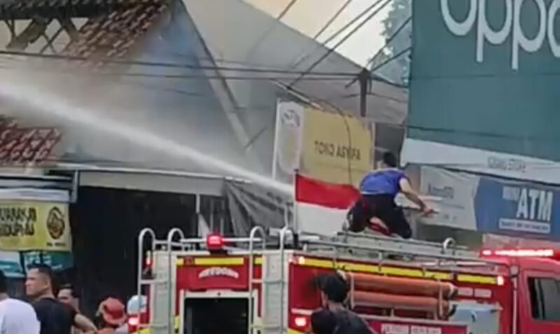 Petugas Damkar saat terus menyemprotkan air ke arah titik lokasi api di rumah toko milik Andi, di Jalan Ir. Juanda, Jalur Dua Kota Agung, Tanggamus, Minggu 13 Juli 2025 | Ist.