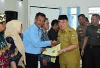 Bupati Tanggamus, Moh. Saleh Asnawi saat menyerahkan Akta Hukum Usaha kepada salah satu perwakilan ketua Kopdes Merah Putih di GFU Islamic Center, Kota Agung, Senin 21 Juli 2025 | Dok. Kominfo Tanggamus.