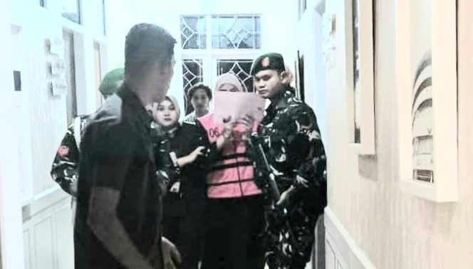 Tersangka Cindy Armila, pegawai Bank BRI Kantor Cabang Pringsewu (menutup wajah) saat digiring Kejati Lampung ke mobil tahanan, Senin 21 Juli 2025, malam | Dok. Kejati Lampung.