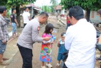Kapolres Tanggamus AKBP Rahmad Sujatmiko saat memberikan sedikit kebahagiaan kepada anak-anak terdampak banjir di Pekon Banding, BNS, Selasa 29 Juli 2025 |