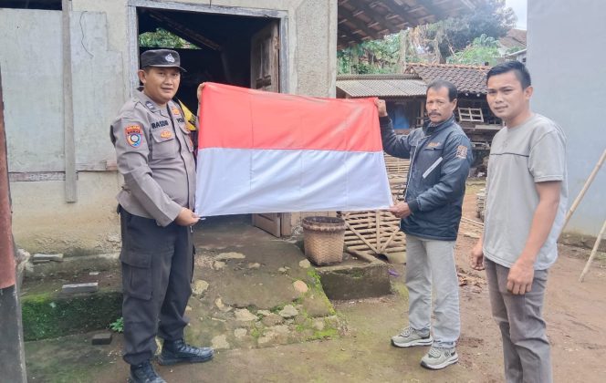 
 Aiptu Rasdin Bhabinkamtibmas Polsek Pulau Panggung Polres Tanggamus saat Memberikan Bendera Merah Putih kepada Masyarakat Pekon Ngarip.