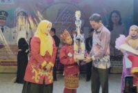 Wabup Tanggamus Agus Suranto saat menyerahkan hadiah kepada Hikmatul Fadilah, pelajar kelas 5 SD asal Pekon Tengor, Kecamatan Cukuh Balak yang berhasil meraih Juara 1 Liga Dangdut 4 Tanggamus 2025 STEBI Tanggamus bekerja sama dengan AWPI Tanggamus berlangsung meriah di Taman Soekarno, Kota Agung, Sabtu malam (25/10/2025) | Herdi/Media Prioritastv.com.