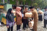 Sekcam Kota Agung Timur Efendi di saksikan kepala SPLP Kotim Basuki saat memberikan cindramata kepada pars guru yang memasuki masa Purna Bakti di SD Negeri 1 Tanjung Anom Kota Agung Timur setelah upacara HUT ke 80 PGRI dan HGN, Selasa (25/11/2025) | Herdi/Media Prioritastv.com.