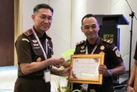 Kepala Kejaksaan Tinggi Lampung, Danang Suryo Wibowo saat menyerahkan penghargaan kepada Irvan Khasbi Assidiqi yang dinobatkan sebagai Jaksa Fasilitator Terbaik se-Provinsi Lampung.