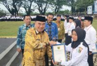 Bupati Tanggamus H. Moh. Saleh Asnawi saat menyerahkan SK PPPK Paruh Waktu kepada perwakilan pegawai di Lapangan Pemkab setempat, Jumat 2 Januari 2025 | Herdi/Media Prioritastv.com.