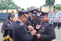 Kapolres Tanggamus AKBP Rahmad Sujatmiko saat menyematkan penghagaan Satyalencana Pengabdian 16 tahun kepada Aipda Epri Mohansyah di Lapangan Mapolres Tanggamus, Jumat 23 Januari 2026 | Dok. Humas Polres Tanggamus.