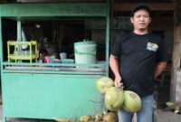Joko, pemilik lapak es kelapa muda di Jalan Bhayangkara depan kantor Pos Kota Agung saat menunjukan jualannya, Senin, 16 Februari 2026 | Sumentri/Media Prioritastv.com.