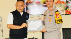 Dr. H Fauzi menyerahkan penghargaan kepada Kapolres Pringsewu sebagai bentuk apresiasi atas komitmen dan keberhasilan penanganan 68 kasus kekerasan anak dan perempuan sepanjang 2025.(foto: Prioritas tv.com/Istimewa)