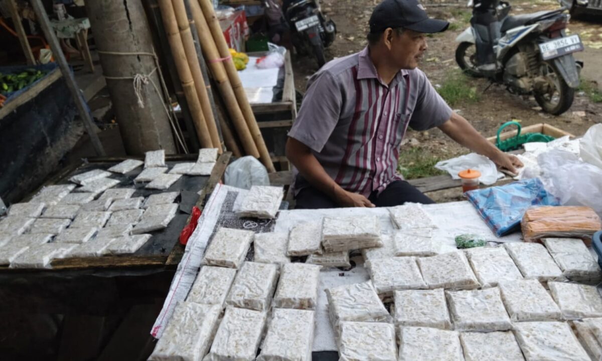 Maman, penjual tempe di Pasar Sarinongko, Pringsewu yang merasakan imbas kenaikan harga plastik saat dikunjungi Jumat 10 April 2026 | Samuel/Media Prioritastv.com.