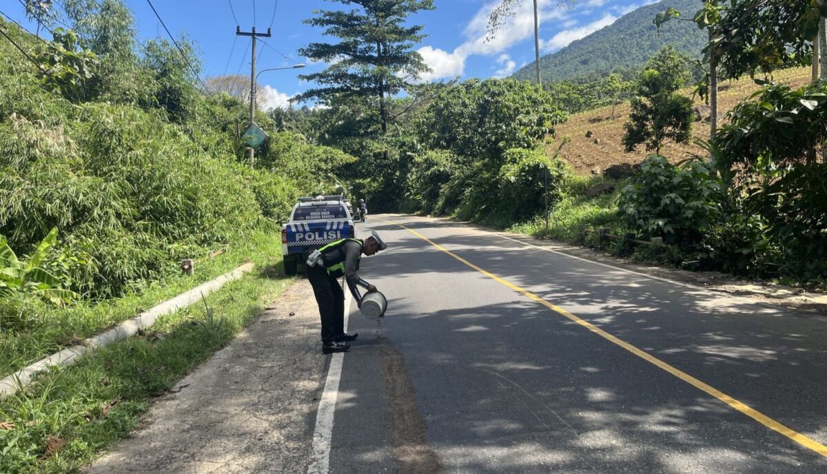 Polisi saat melakukan penyiraman pasir di lokasi tergelincirnya pemotor di Pekon Batu Kramat, Kota Agung Timur, Tanggamus, Jumat 29 Mei 2026 | Dok. Humas Polres Tanggamus.