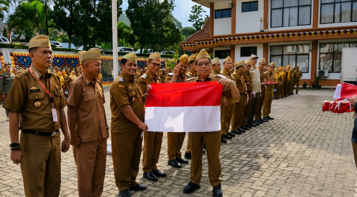 Sekda Tanggamus Suadi saat menyerahkan bendera merah putih kepada Kadis Perhubungan M. Sabar Sitanggang usai apel di Lapangan belakang kantor  Bupati, Senin 10 Agustus 2026 | Herman/Media Prioritastv.com.
