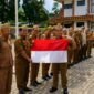 Sekda Tanggamus Suadi saat menyerahkan bendera merah putih kepada Kadis Perhubungan M. Sabar Sitanggang usai apel di Lapangan belakang kantor  Bupati, Senin 10 Agustus 2026 | Herman/Media Prioritastv.com.