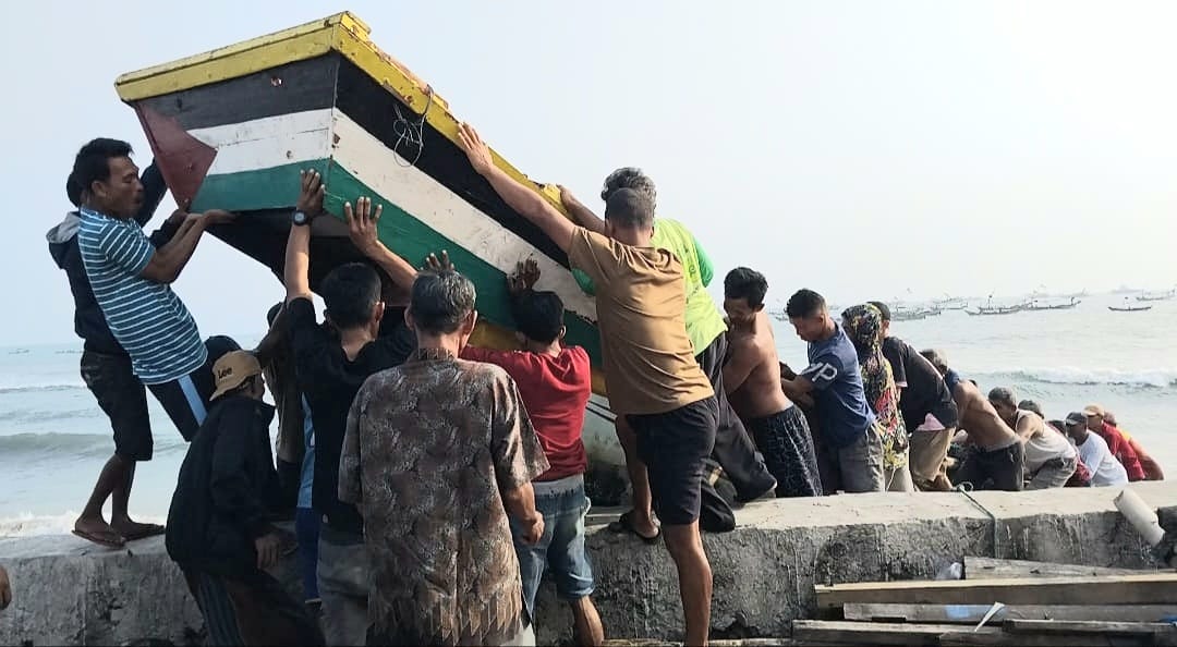 Nelayan saat bergotong royong mengevakuasi perahu yang rusak diterjang gelombang tinggi, Rabu 12 Agustus 2026 | Herdi/Media Prioritastv.com.