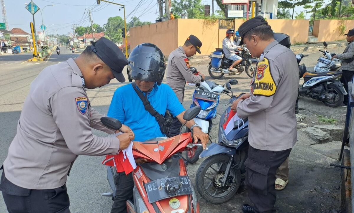 Pembagian dan pemasangan bendera merah putih oleh anggota Polsek Kota Agung di Jalinbar Tanggamus, Minggu 16 Agustus 2026 | Dok. Humas Polres Tanggamus.