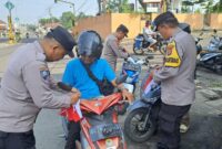 Pembagian dan pemasangan bendera merah putih oleh anggota Polsek Kota Agung di Jalinbar Tanggamus, Minggu 16 Agustus 2026 | Dok. Humas Polres Tanggamus.